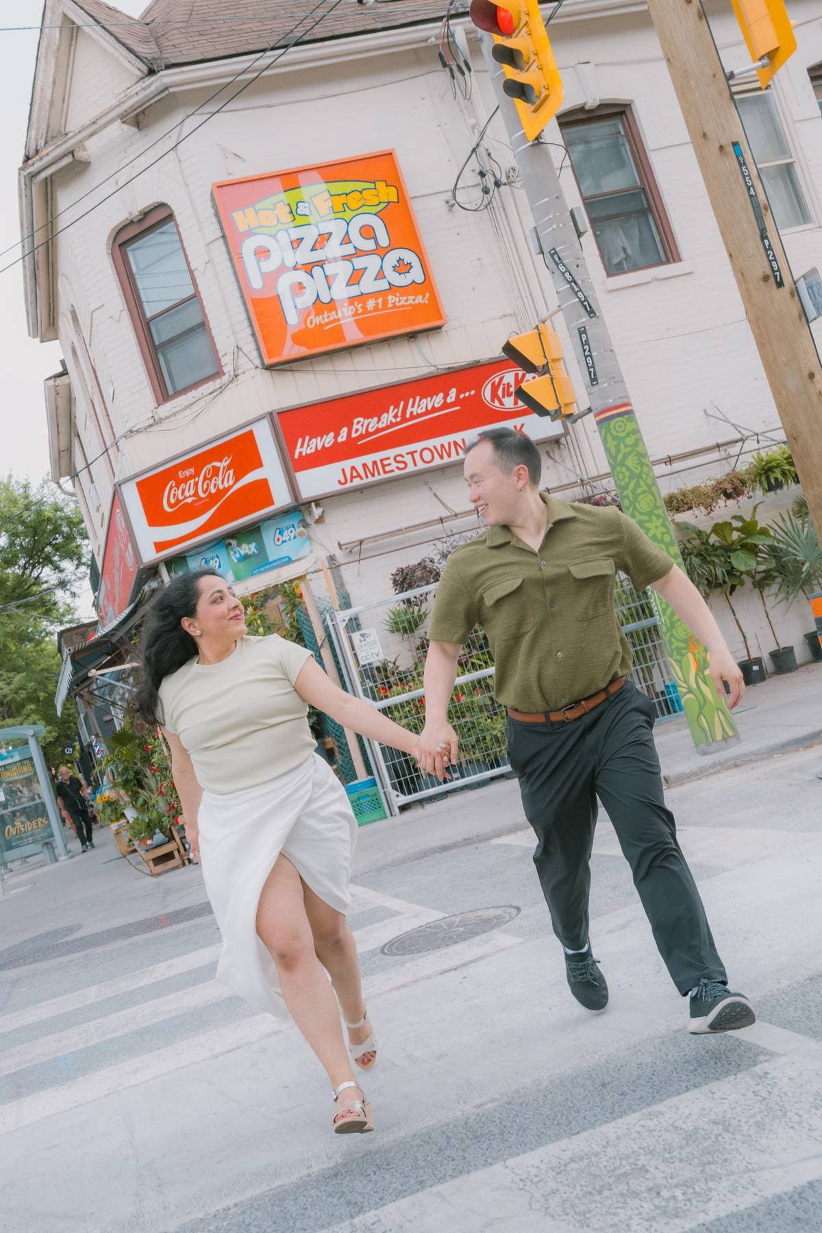 Sanjika and Andy laughing while crossing a street hand in hand