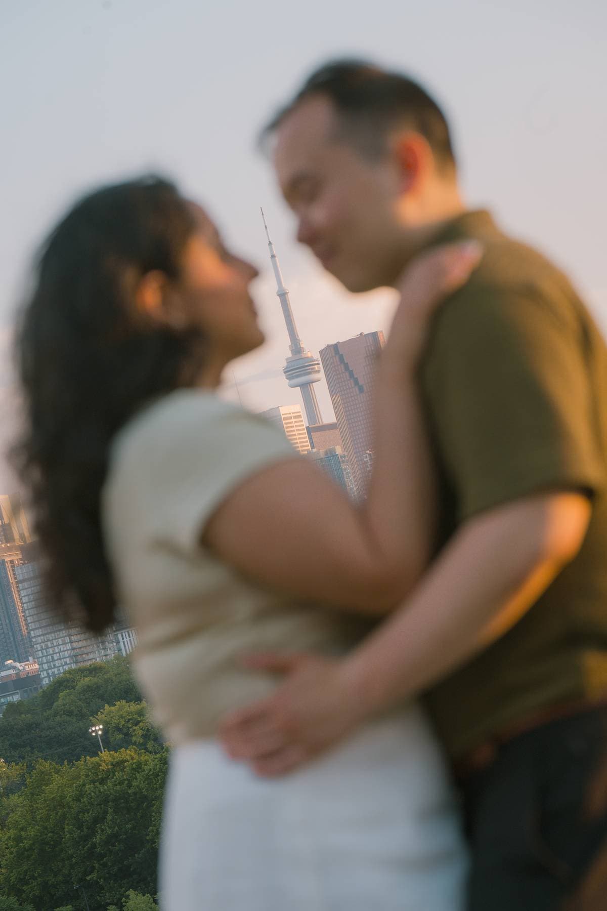 Sanjika and Andy embracing at sunset with the Toronto skyline behind them
